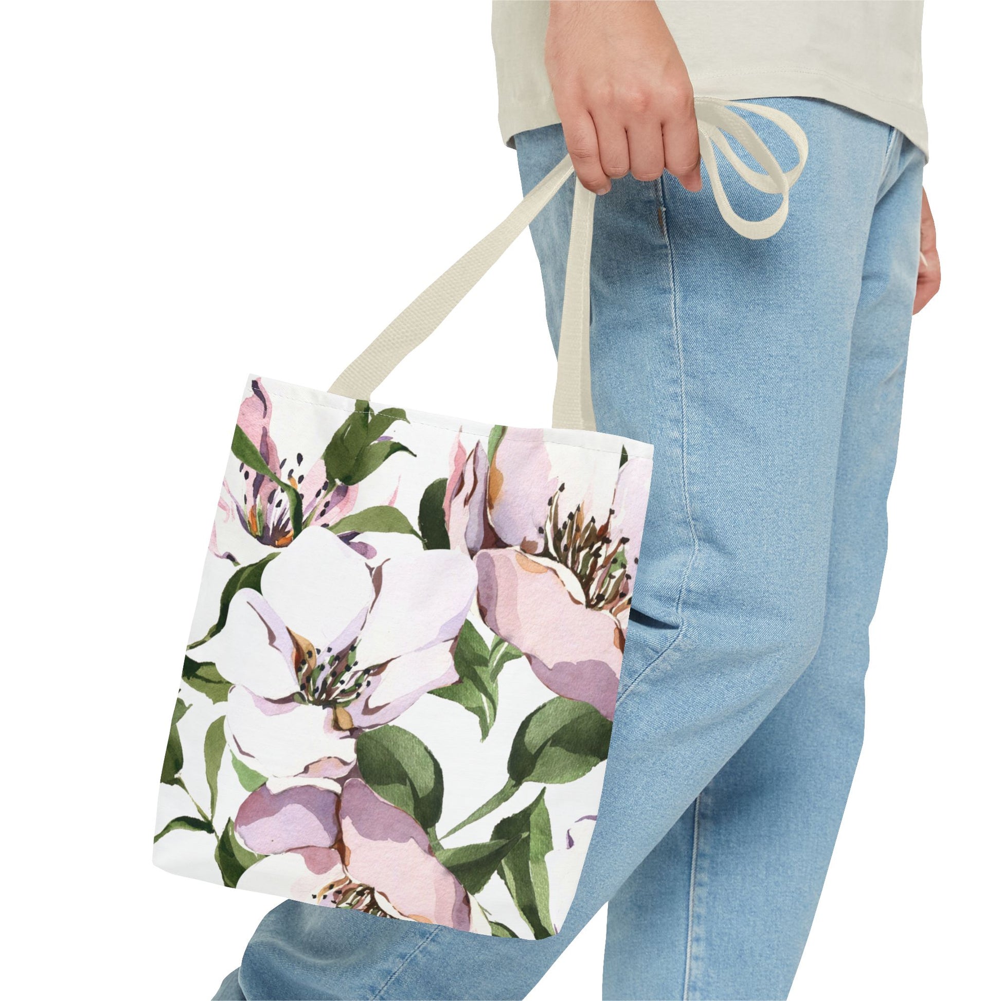 Floral tote bag held by a person wearing light blue jeans on a white background