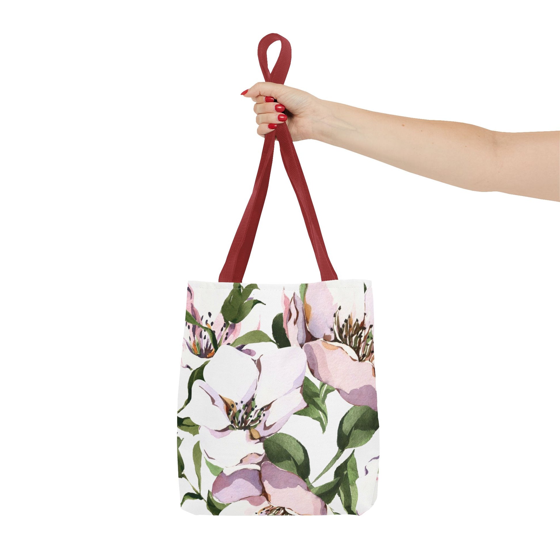 Floral tote bag with a hand holding the strap on a white background