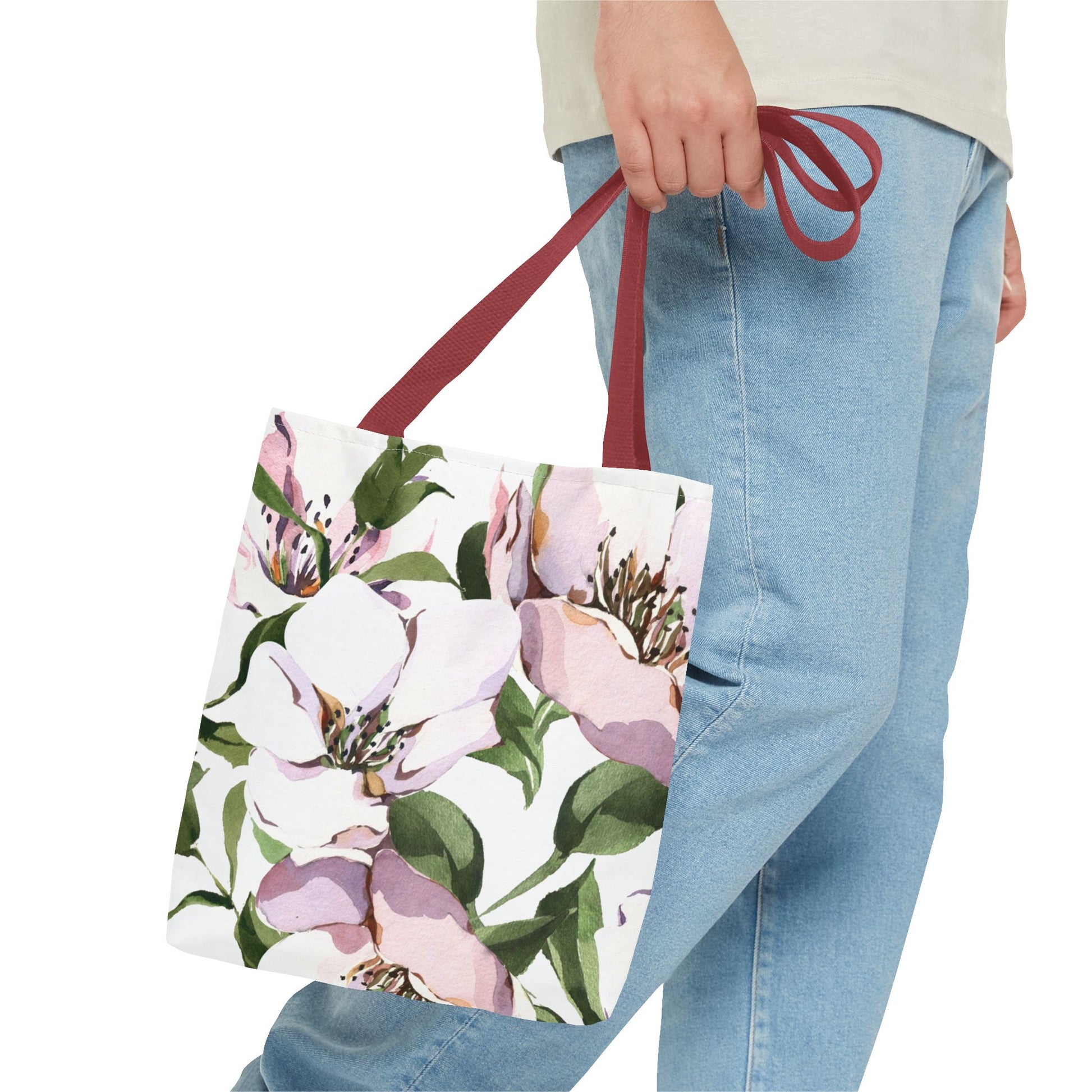 Floral tote bag held by a person wearing blue jeans on a white background