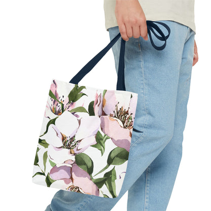 Floral tote bag held by a person wearing blue jeans on a white background